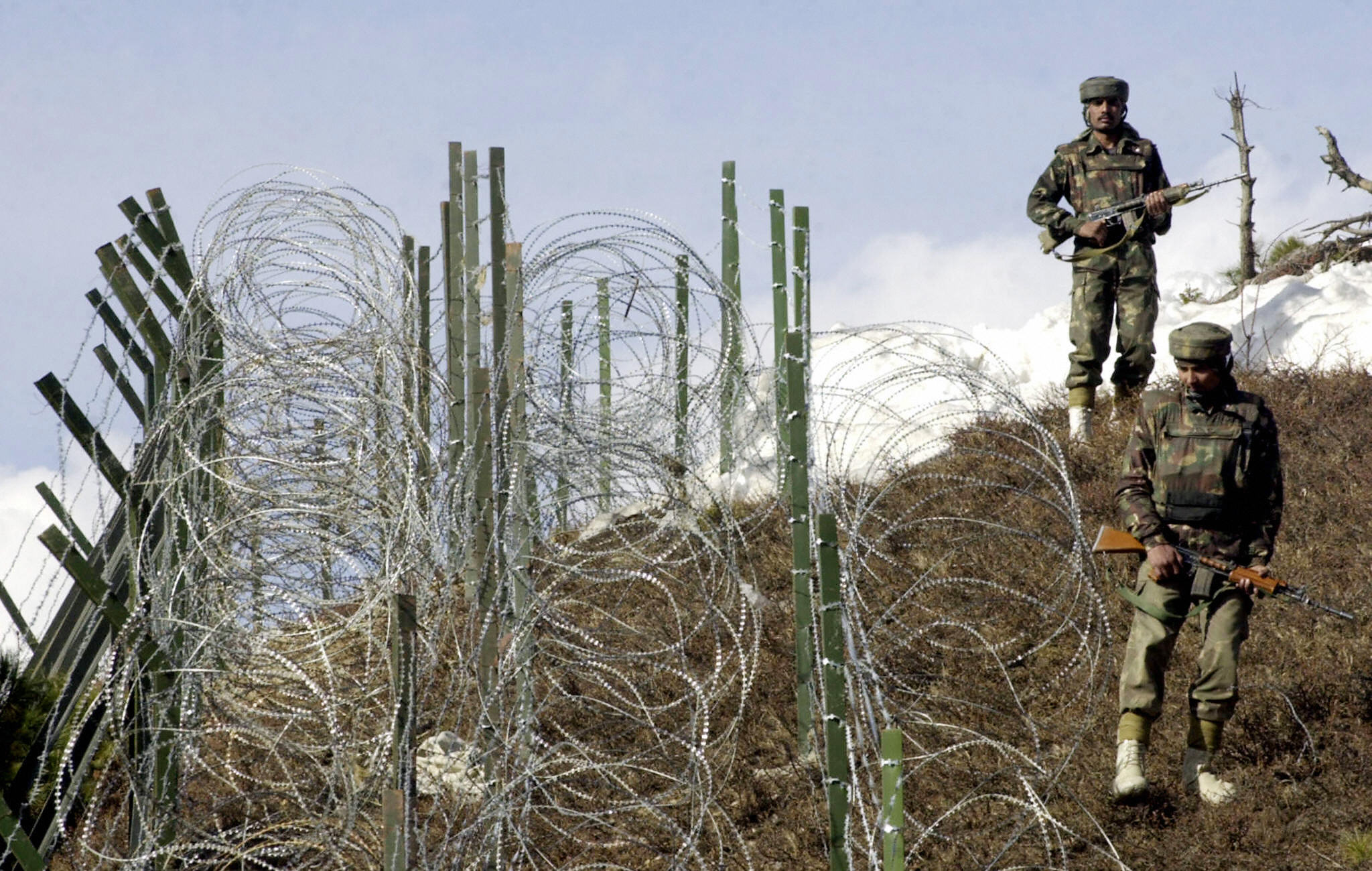 Indian soldiers patrol along a barbed-wire fence, 04 December 2003, near Baras Post on the Line of Control (LoC) between Pakistan and India some 174 kilometers north west of Srinagar. (SAJJAD HUSSAIN/AFP via Getty Images)
